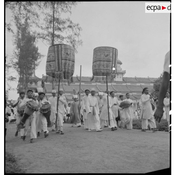 Pham Cong Tac, haut-dignitaire caodaïste, marchant aux côtés de fidèles.