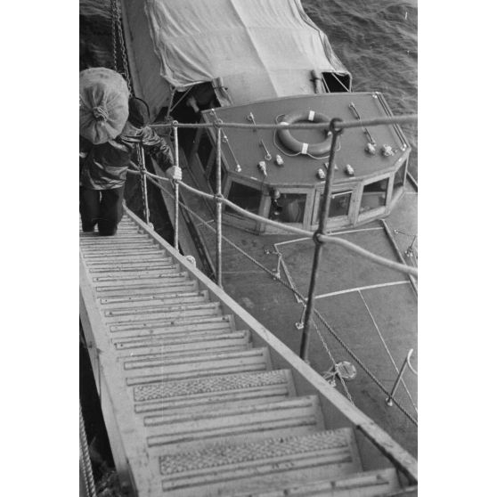 Du ravitaillement, déchargé d'une embarcation de moyenne taille, est chargé à bord d'un dragueur de mines allemand (Sperrbrecher).