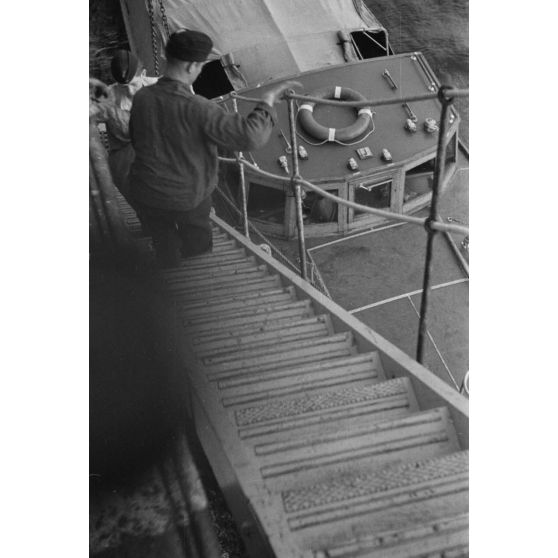 Du ravitaillement, déchargé d'une embarcation de moyenne taille, est chargé à bord d'un dragueur de mines allemand (Sperrbrecher).