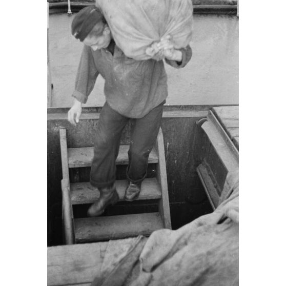 Du ravitaillement, déchargé d'une embarcation de moyenne taille, est chargé à bord d'un dragueur de mines allemand (Sperrbrecher).