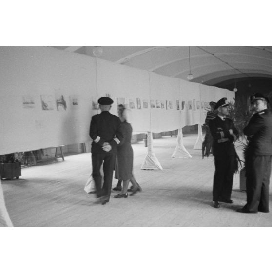 Des officiers de la marine allemande (Kriegsmarine) visitent une exposition de peintures (gouache et aquarelle).