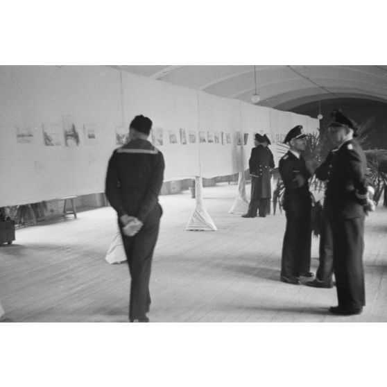 Des officiers de la marine allemande (Kriegsmarine) visitent une exposition de peintures (gouache et aquarelle).