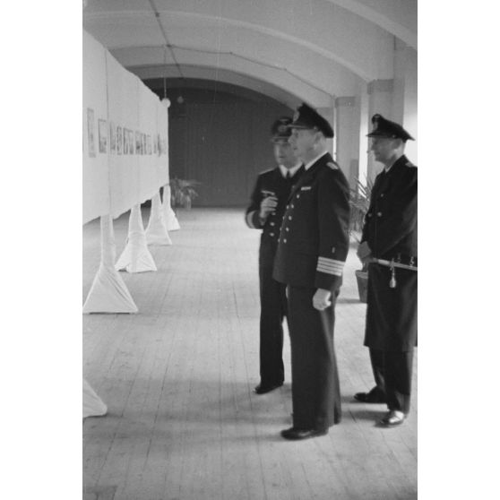 Des officiers de la marine allemande (Kriegsmarine) visitent une exposition de peintures (gouache et aquarelle).