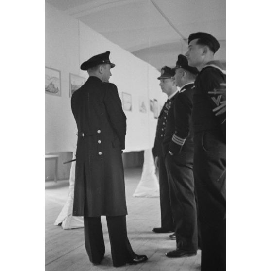 Des officiers de la marine allemande (Kriegsmarine) visitent une exposition de peintures (gouache et aquarelle).