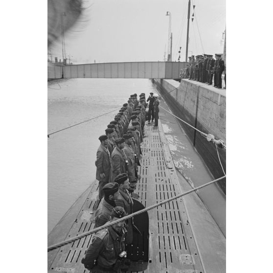 Lors de son retour de croisière à Saint-Nazaire, un officier de la 7.Unterseebootsflottille passe en revue l'équipage du sous-marin U-552 en compagnie de son commandant le lieutenant (Leutnant zur See) Erich Topp.