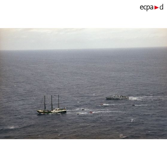 Vue aérienne du navire Rainbow Warrior II de l'association Greenpeace après son arraisonnement escorté par le patrouilleur La Tapageuse (P691) et cinq zodiacs, à proximité de l'atoll de Morurua.