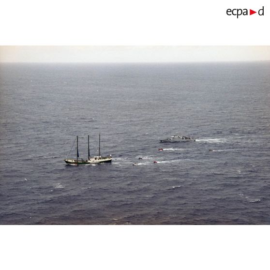 Vue aérienne du navire Rainbow Warrior II de l'association Greenpeace après son arraisonnement escorté par le patrouilleur La Tapageuse (P691) et cinq zodiacs, à proximité de l'atoll de Morurua.
