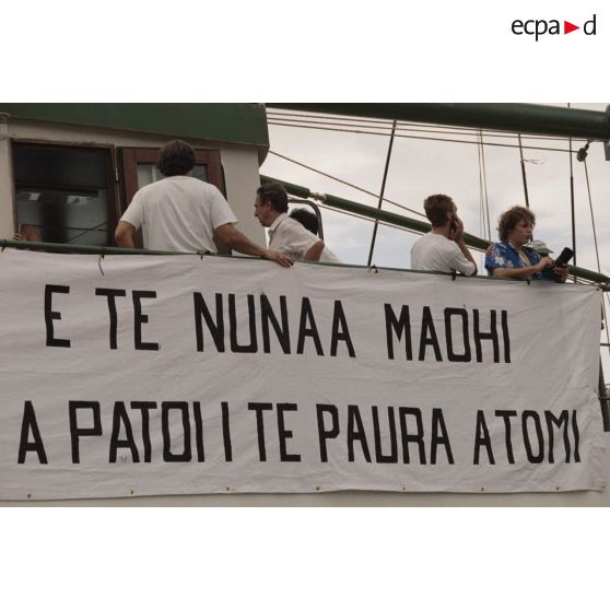 Equipage et banderole "a te nunaa maohi a patoi te paura atomi" (des peuples autochtones contre la bombe atomique) à bord du navire Rainbow Warrior 2  de l'association Greenpeace à quai dans le port de Papeete.