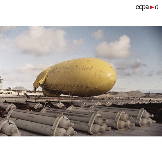Un ballon captif sur son aire de gonflage au poste de commandement de tir (PCT) à Anémone du centre d'expérimentations du Pacifique (CEP) sur l'atoll de Moruroa. Au premier plan, alignement de bonbonnes de gaz.
