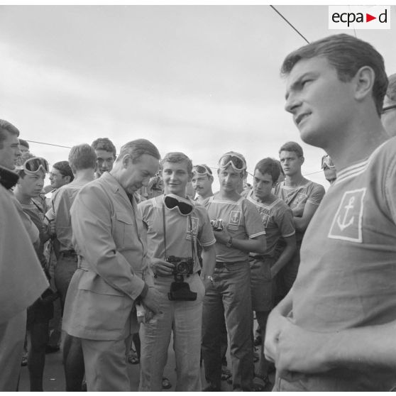 Michel Debré, ministre d'Etat chargé de la Défense, suite à l'expérience atomique du tir Licorne du 3 juillet 1970, s'entretient avec les jeunes marins du croiseur de commandement De Grasse  équipés de lunettes de protection.