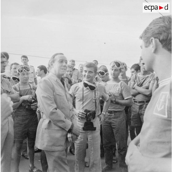 Michel Debré, ministre d'Etat chargé de la Défense, suite à l'expérience atomique du tir Licorne du 3 juillet 1970, s'entretient avec les jeunes marins du croiseur de commandement De Grasse équipés de lunettes de protection.