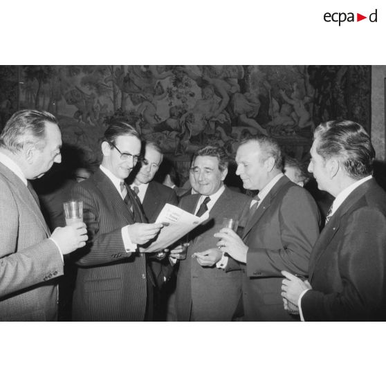 Robert Galley, ministre des Armées, donne un cocktail en l'honneur des journalistes spécialisés ayant participé au voyage en Polynésie française, et reçoit leurs voeux dans les salons de l'hôtel de Brienne. Consultation d'un journal.