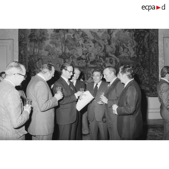 Robert Galley, ministre des Armées, donne un cocktail en l'honneur des journalistes spécialisés ayant participé au voyage en Polynésie française, et reçoit leurs voeux dans les salons de l'hôtel de Brienne. Consultation d'un journal.