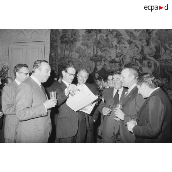 Robert Galley, ministre des Armées, donne un cocktail en l'honneur des journalistes spécialisés ayant participé au voyage en Polynésie française, et reçoit leurs voeux dans les salons de l'hôtel de Brienne. Consultation d'un journal.