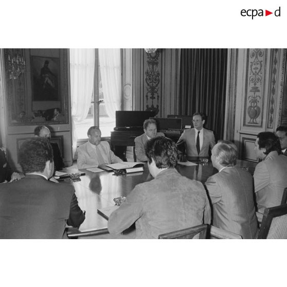 Charles Hernu, ministre de la Défense, entouré de membres de son cabinet, reçoit en audience une délégation d'élus de la Polynésie française conduite par Gaston Flosse (de dos).