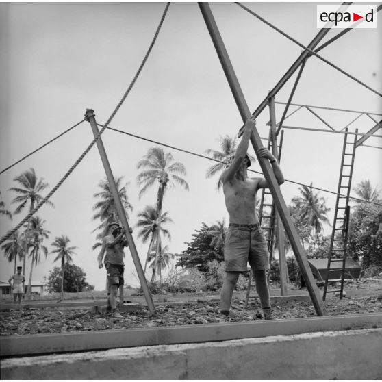 Montage de la structure métallique d'un hangar. Militaires du 5e régiment mixte du Pacifique (5e RMP). Peut-être la construction du camp d'Arue, vers 1963-1964.