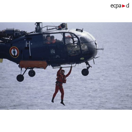 Gros plan sur une opération d'hélitreuillage de personnel sur le pont du ferry Corse depuis l'hélicoptère Alouette-III de l'aéronavale.