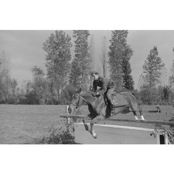 Sous les yeux d'un instructeur, il pourrait s'agir du Major Lippert, un sous-officier allemand saute les obstacles en compagnie de sa monture.