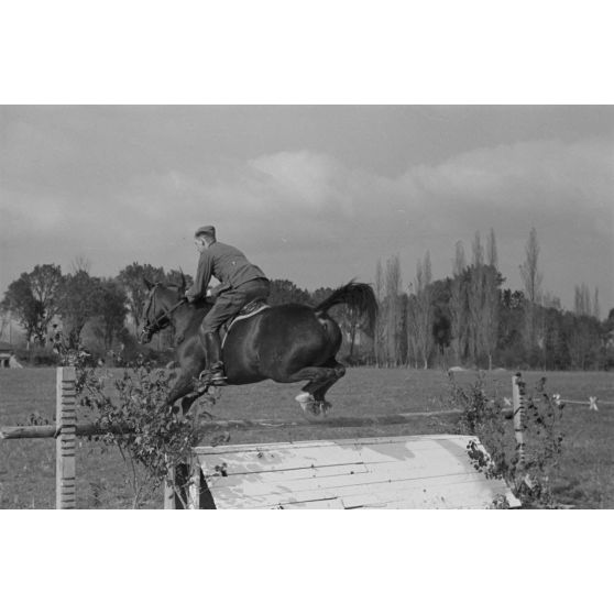 Sous les yeux d'un instructeur, il pourrait s'agir du Major Lippert, un sous-officier allemand saute les obstacles en compagnie de sa monture.