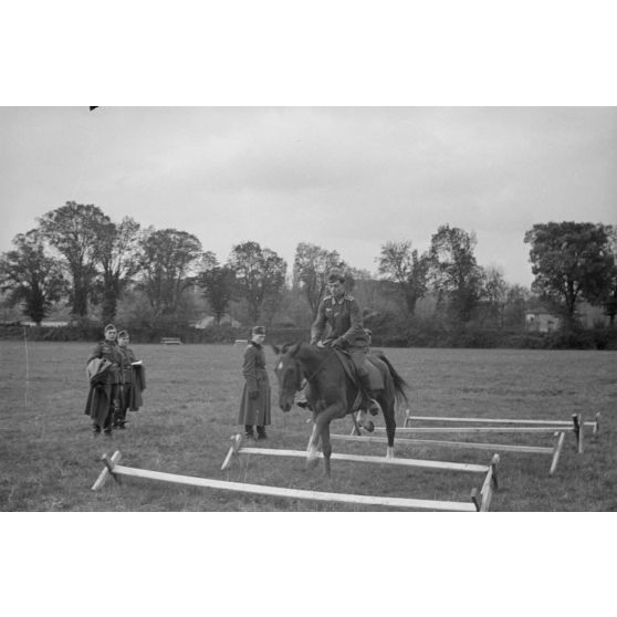 Sous les yeux d'un instructeur, il pourrait s'agir du Major Lippert, un sous-officier allemand saute les obstacles en compagnie de sa monture.