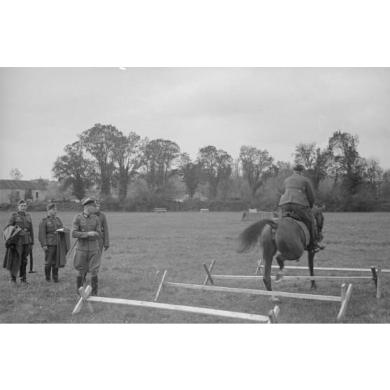 Sous les yeux d'un instructeur, il pourrait s'agir du Major Lippert, un sous-officier allemand saute les obstacles en compagnie de sa monture.