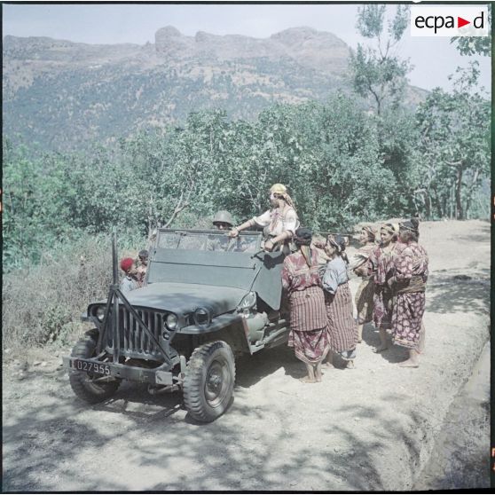 Le 7e Bataillon de chasseurs alpins (BCA) en patrouille dans un village kabyle. Des femmes et des enfants veulent monter à bord d'une jeep.