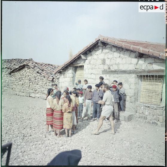 Kabylie. 27e Bataillon de chasseurs alpins (BCA). L'instituteur avec ses élèves devant l'école pour faire un jeu.