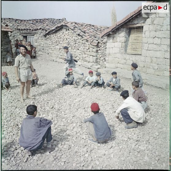 Kabylie. 27e Bataillon de chasseurs alpins (BCA). L'instituteur avec ses élèves devant l'école pour faire un jeu.