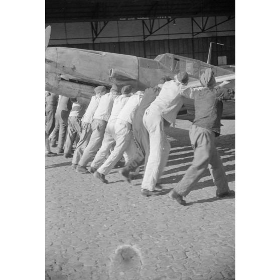 Des mécaniciens du Ergänzungsgruppe Süd positionnent un chasseur Messerschmitt Bf-109 qui porte le numéro 12.