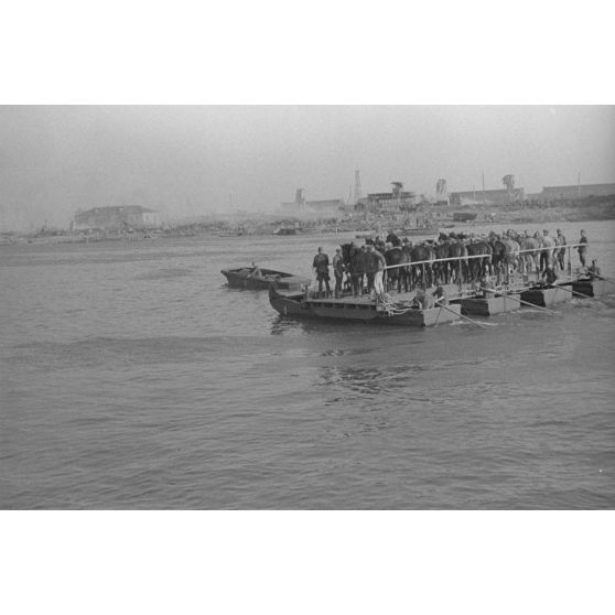 Des soldats et des chevaux traversent le cours d’eau à bord d’une barge.