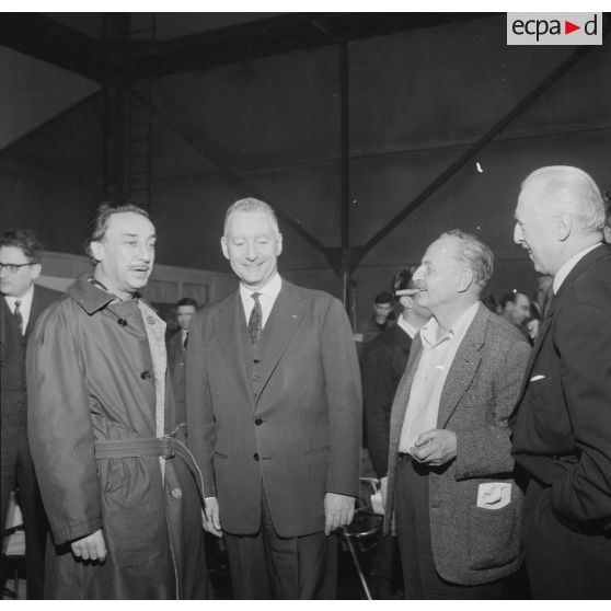 Projection en avant-première aux studios de Boulogne du film Le jour le plus long. Pierre Messmer, ministre des Armées, le général Pierre Koenig, conseiller militaire du film, et Darryl Zanuck, producteur du film, discutent avec l'écrivain Romain Gary, contribuant au scénario du film, lors du tournage.