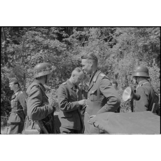 Des officiers de la FlaK échangent avec un soldat de l'armée de terre allemande.