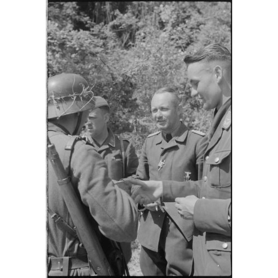 Des officiers de la FlaK échangent avec un soldat de l'armée de terre allemande.