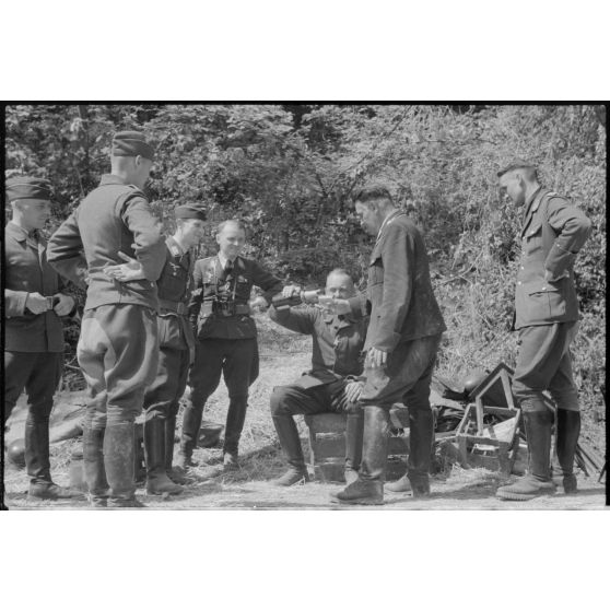 Des officiers de la FlaK et des membres de la Luftwaffe Kriegsberichter Kompanie 4 partagent une bouteille.