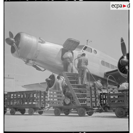Sur l'aéroport de Marignane, des sacs postaux sont déchargés de l'avion de transport Dewoitine D338 ARTC de la compagnie Air France.