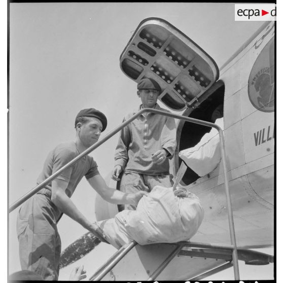 Sur l'aéroport de Marignane, des sacs postaux sont déchargés de l'avion de transport Dewoitine D338 ARTC de la compagnie Air France.