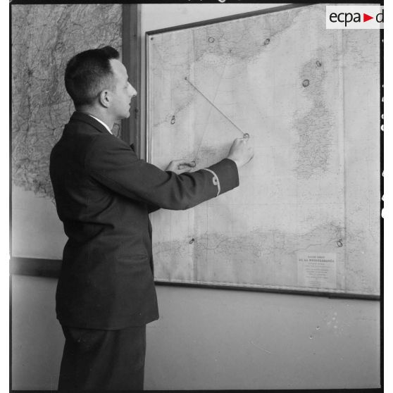 Personnel d'Air France, a priori un chef de cabine, devant une carte figurant les liaisons aériennes de la compagnie.