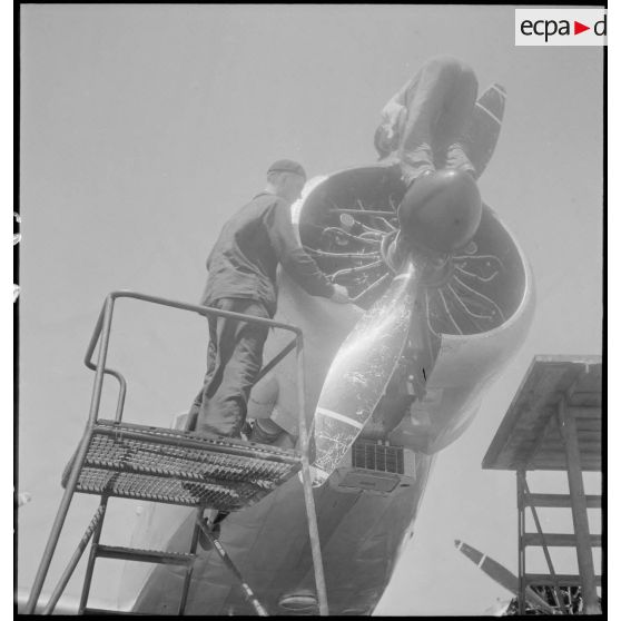 Sur l'aéroport de Marignane, des mécaniciens assurent la maintenance du moteur principal d'un avion de transport Dewoitine D338 d'Air France de retour de liaison.
