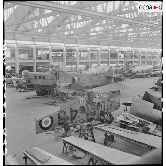 Montage, au premier plan, d'un bombardier Bloch MB 210 sous un hangar de l'atelier de réparation de l'armée de l'Air (ARAA), sur l'aérodrome de Toulouse.
