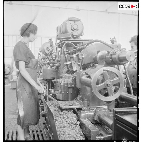 Des ouvrières de l'atelier de réparation de l'armée de l'Air (ARAA) de Limoges usinent des pièces de moteurs d'avions sur une machine-outil.