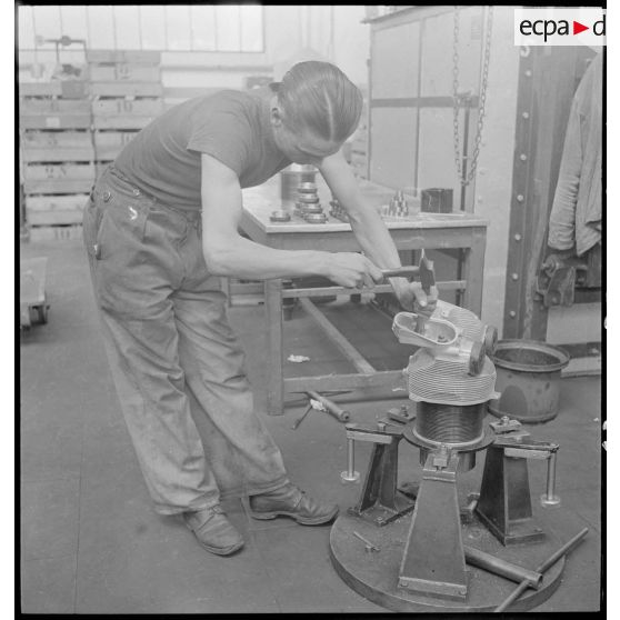 Un ouvrier de l'atelier de réparation de l'armée de l'Air (ARAA) de Limoges ajuste une pièce de moteur d'avion.