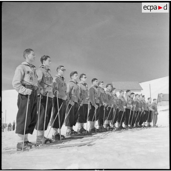 Présentation des équipes participantes avant un concours de ski de l'organisation Jeunesse et Montagne dans les Alpes.