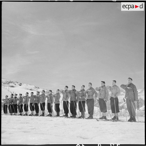 Salut et prestation de serment des équipes participantes avant un concours de ski de l'organisation Jeunesse et Montagne dans les Alpes.