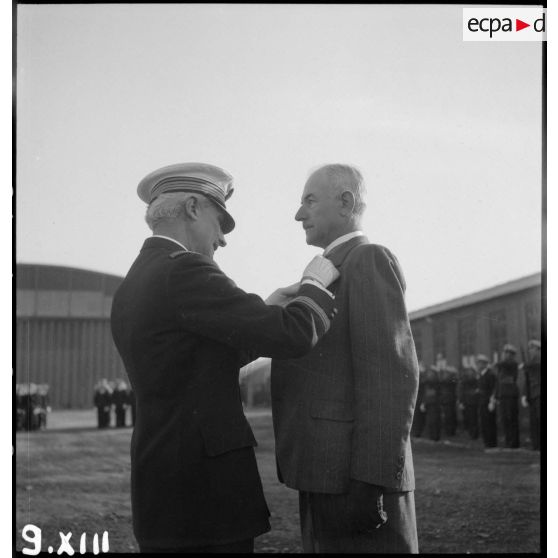 Un commandant remet la croix d'officier de la Légion d'honneur à un civil lors d'une prise d'armes sur l'aérodrome de Vichy-Rhue.