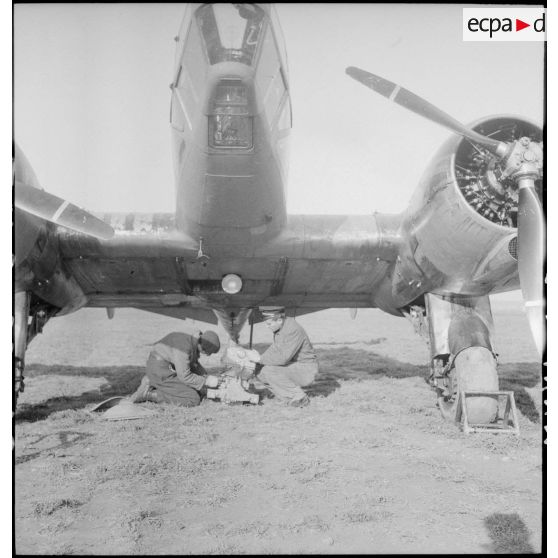 Mise en place d'une mitrailleuse sous le fuselage d'un avion d'observation Potez 63-11 avant un départ en mission.