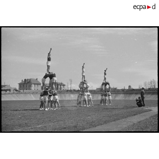 Salut olympique d'athlètes de l'armée de l'Air en haut de pyramides humaines réalisées lors d'une manifestation sportive sur le stade de Vichy.