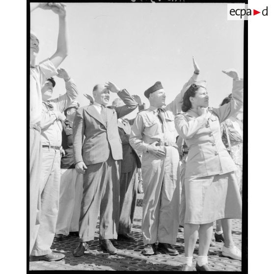 M. Grenier ainsi que le général Bouscat et les gagnants du tirage de la tombola admirent les acrobaties d'un chasseur sur le terrain de Réghaia.