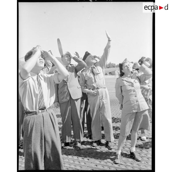 M. Grenier ainsi que le général Bouscat et les gagnants du tirage de la tombola admirent les acrobaties d'un chasseur sur le terrain de Réghaia.