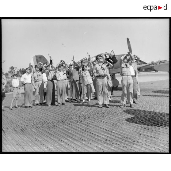 M. Grenier ainsi que le général Bouscat et les gagnants du tirage de la tombola admirent les acrobaties d'un chasseur sur le terrain de Réghaia.