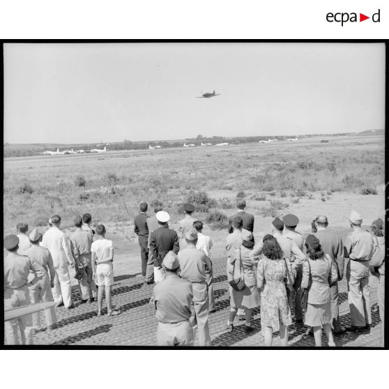 M. Grenier ainsi que le général Bouscat et les gagnants du tirage de la tombola admirent les acrobaties d'un chasseur sur le terrain de Réghaia.